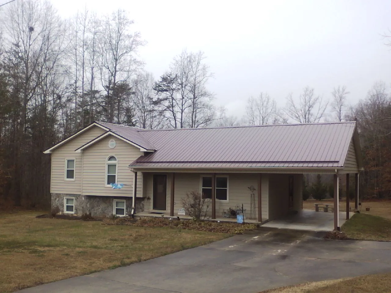 Burgundy metal roof on a tan split level home with an attached carport in Akron