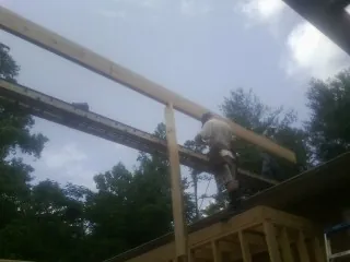 Carpenter setting a ridge beam over a new addition frame — Ice Dam Removal by Roofing Brothers in Akron